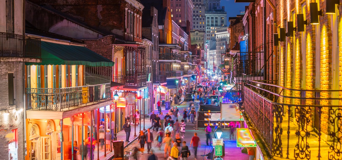 A lit-up street during the New Orleans Mardi gras with colorful neon lights.